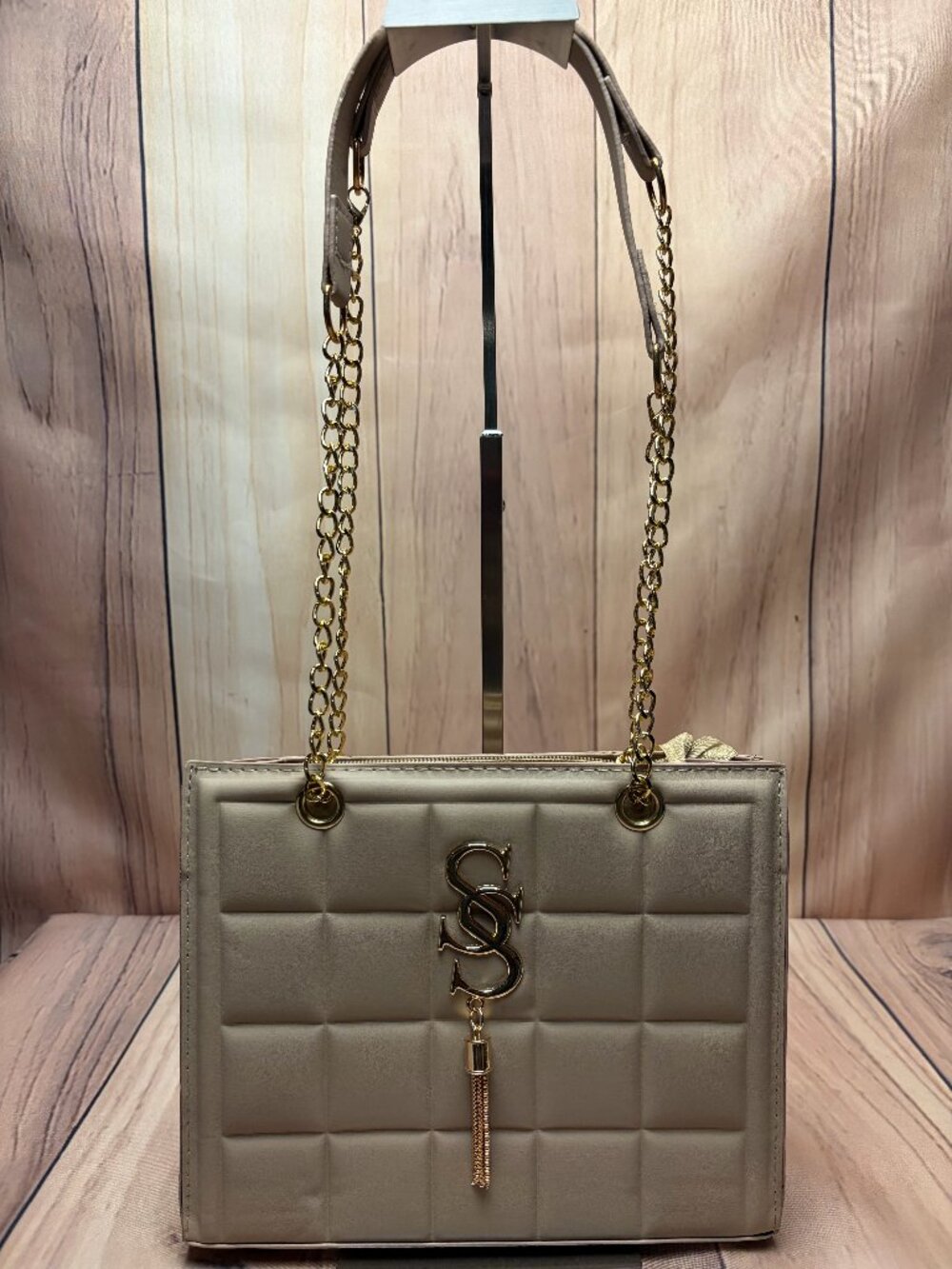 Beige quilted handbag featuring elegant gold-tone hardware, chain detailing